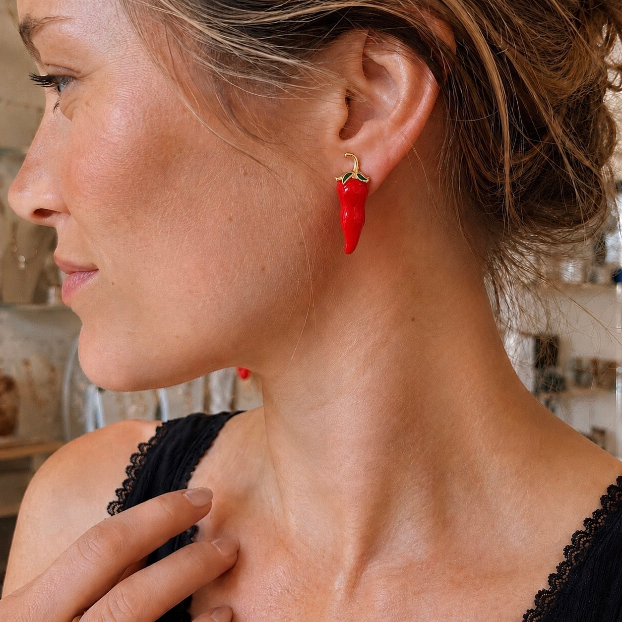 Close-up of a woman wearing red chili pepper earrings.