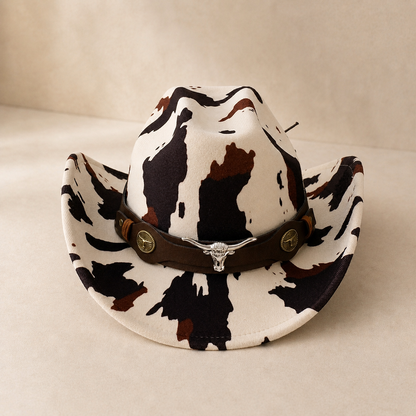 Cow print cowboy hat with a brown band on a beige background